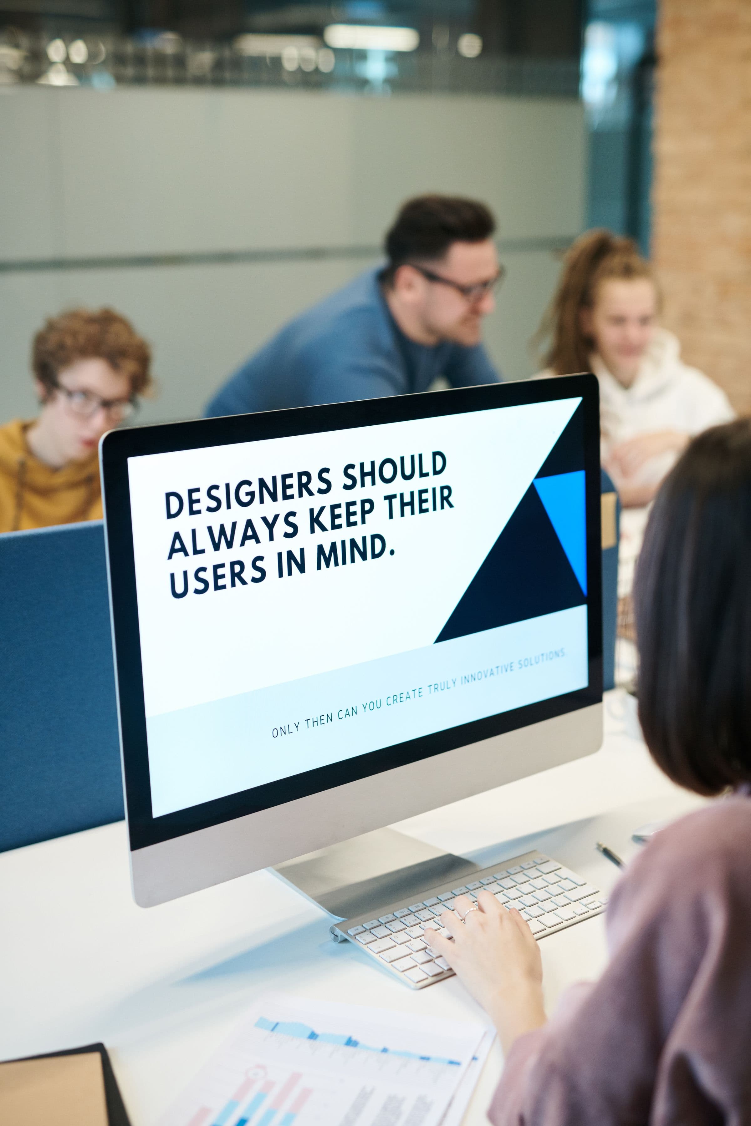 Product design team reviewing user behavior around a desktop screen.